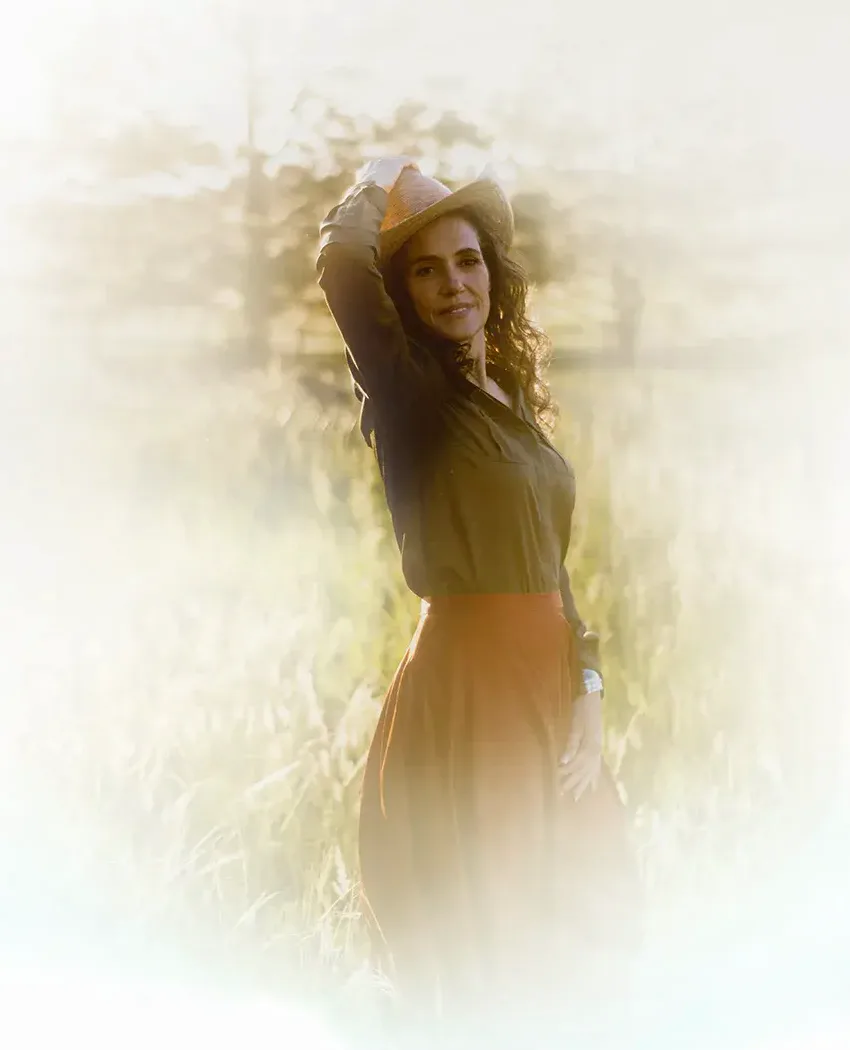 Laura in a sun hat standing in a sunlit meadow